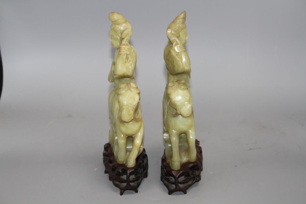 A pair of Chinese bowenite jade groups of a lady riding a horse, wood stands total height 26.5 and 27cm